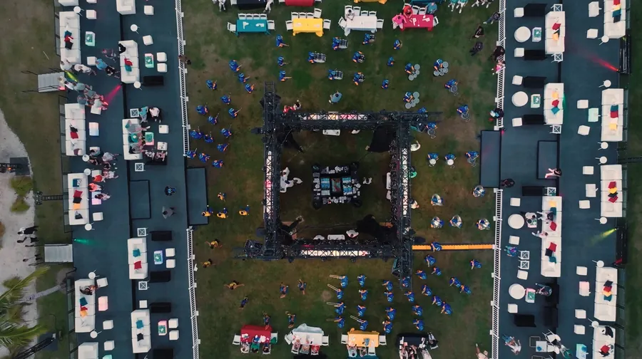 Aerial drone view of the Baha Mar Big Game Tailgate event showing a large outdoor setup with lounge seating, colorful tables, stage trussing, and guests on the lawn.